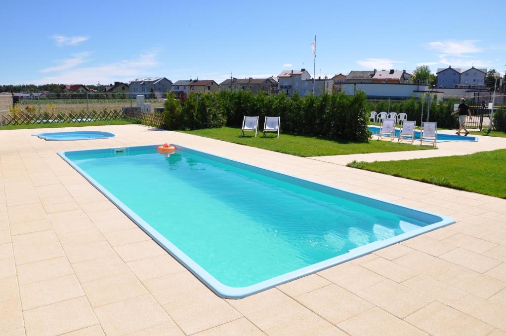 uma grande piscina com duas cadeiras num quintal em Lawendowa Wyspa Klub Nadmorski em Ostrowo