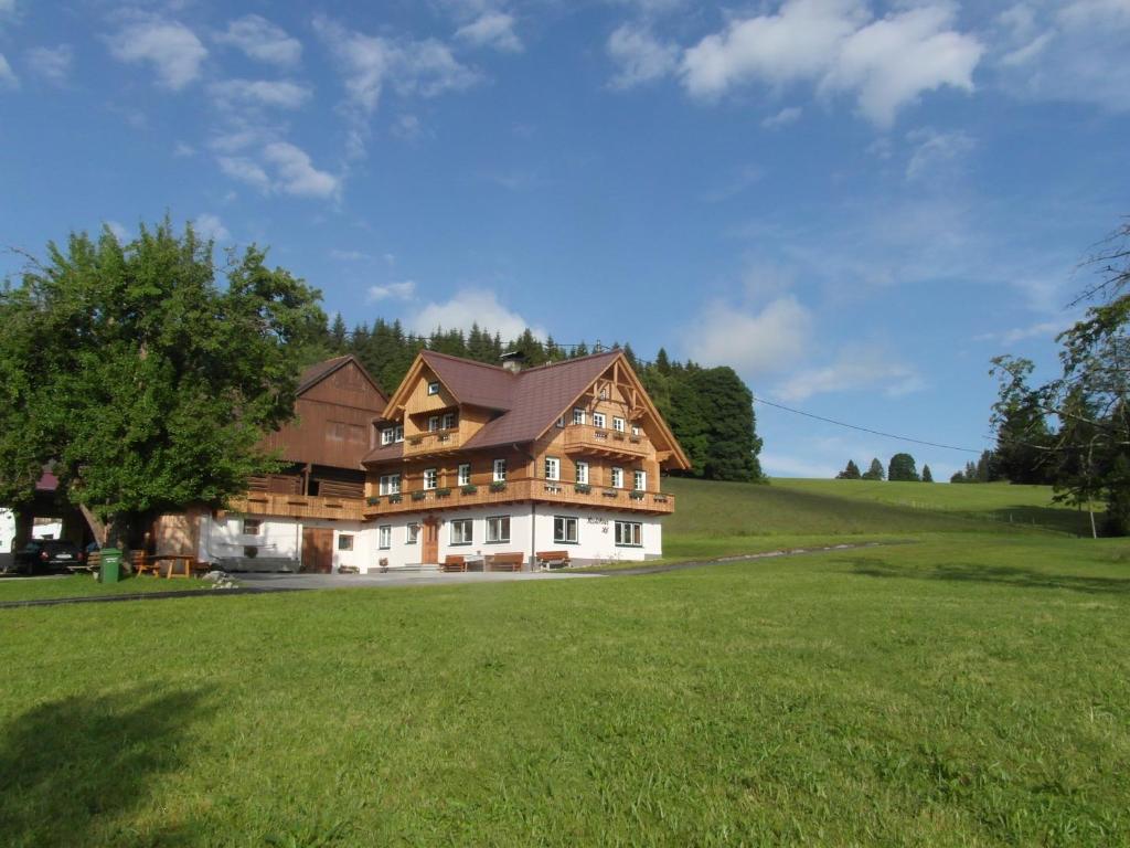 een groot huis op een heuvel met een groen veld bij Haslehnerhof in Ramsau am Dachstein