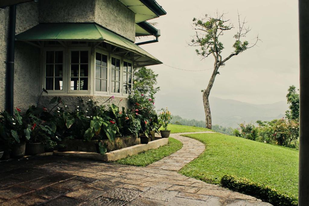 a house with a pathway leading to a window and a tree at Hatale Tea Estate Bungalow in Madulkele