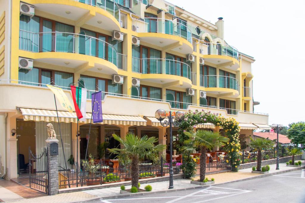 a large yellow building with palm trees in front of it at Hotel Energy in Kiten