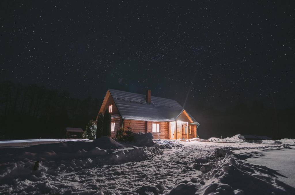 a wooden cabin in the snow at night at Pakrasti in Svente