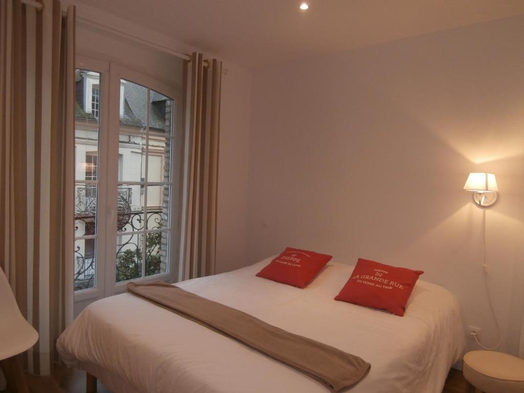 ein Schlafzimmer mit einem Bett mit zwei roten Kissen darauf in der Unterkunft au Claire de lune in Dieppe