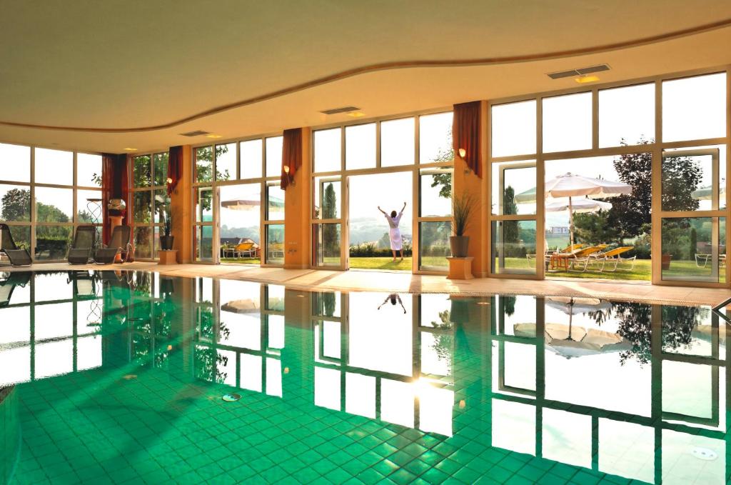 einem Pool mit einer Person, die in den Fenstern eines Gebäudes steht in der Unterkunft Hotel Stenitzer in Bad Gleichenberg