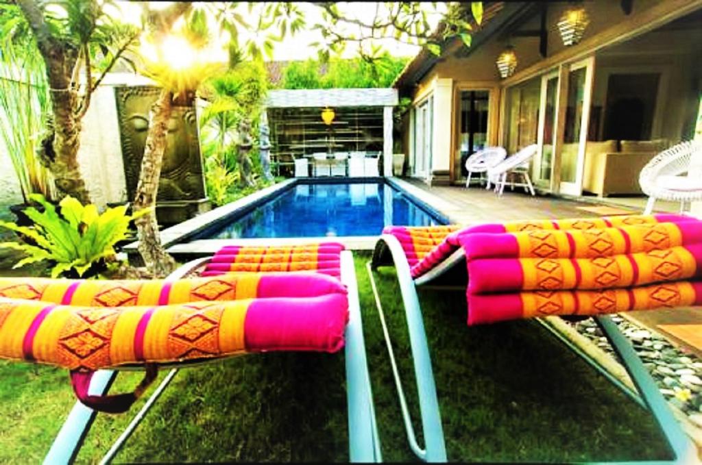 a pool with two lounge chairs next to a house at Bamboo Moon Villas in Sanur
