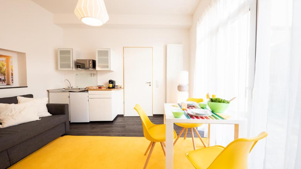 a kitchen and living room with a table and yellow chairs at Relax Aachener Boardinghouse Phase 2 in Aachen