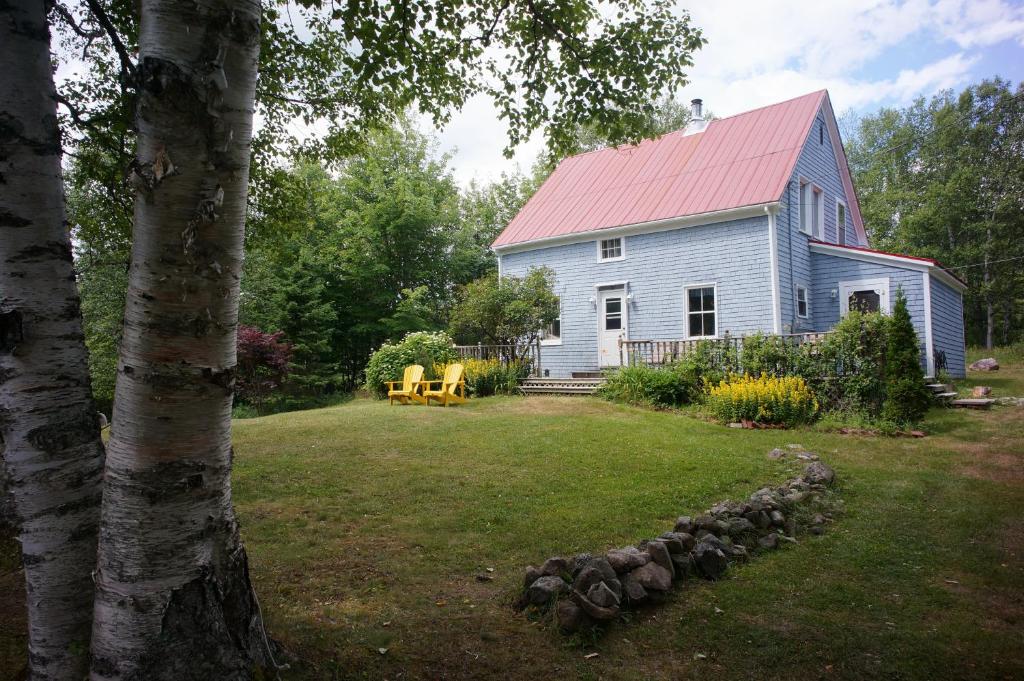 Casa blanca con techo rojo y patio en Maggie's Place on the Cabot Trail, en Birch Plain