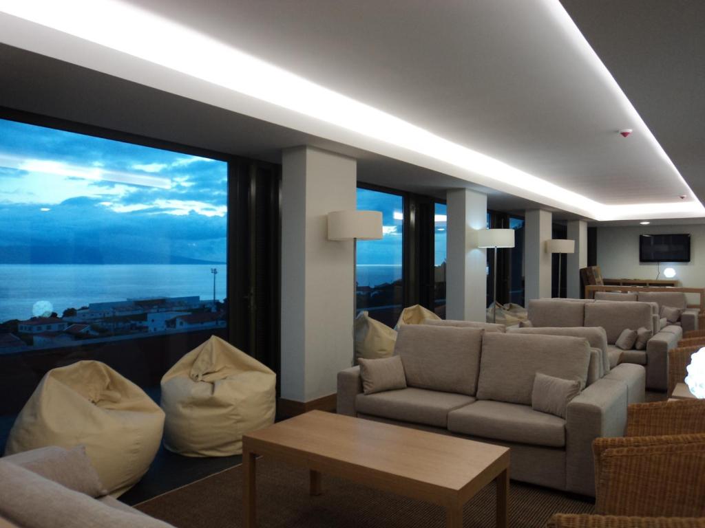 a living room with couches and a large window at Azores Youth Hostels - São Jorge in Calheta