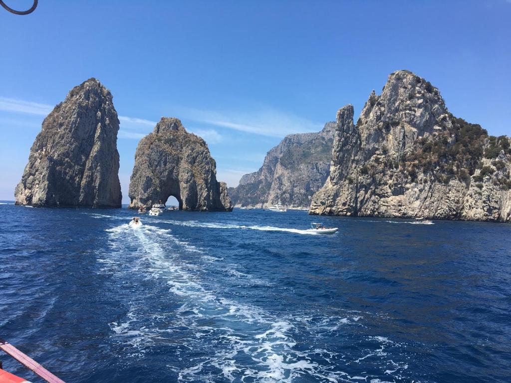 a boat in the water near some rocky islands at PEPPE'S HOME Luxury and relax apartament in Gragnano