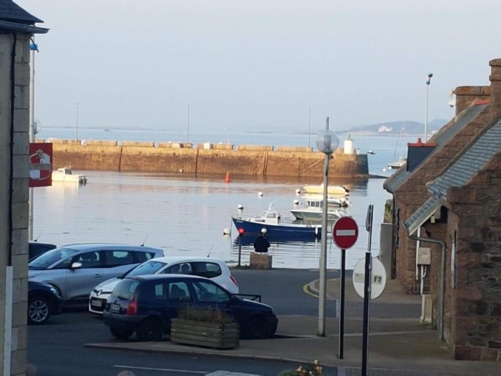 un groupe de voitures garées sur un parking avec un bateau dans l'eau dans l'établissement Appartement LE TRITON, à Perros-Guirec