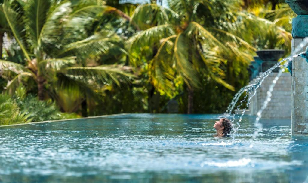 a woman swimming in a pool with a fountain at Four Seasons Resort Langkawi in Tanjung Rhu