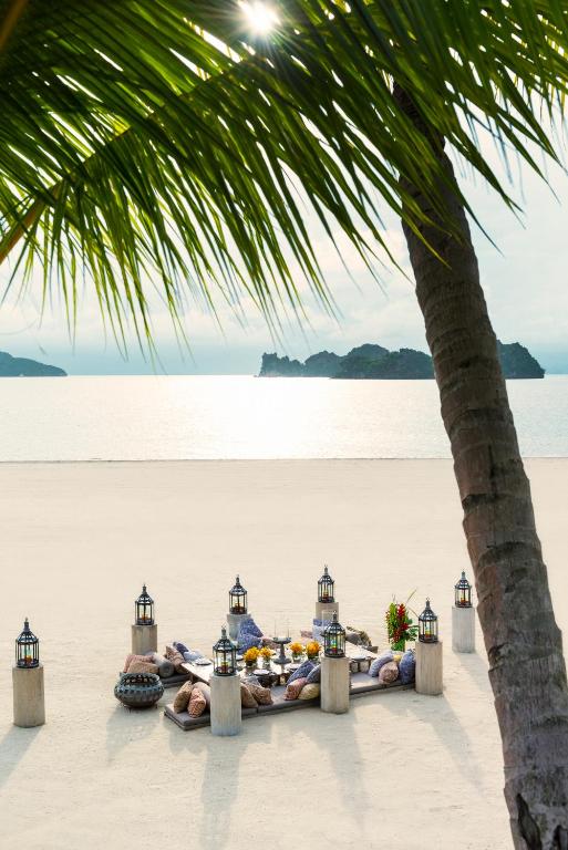 a table on the beach under a palm tree at Four Seasons Resort Langkawi in Tanjung Rhu