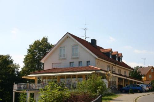 uma grande casa branca com um alpendre numa rua em Hotel Café Talblick em Vielbrunn