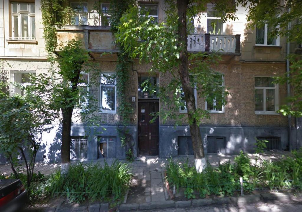 een bakstenen gebouw met een zwarte deur en bomen bij Apartment on Khorvatska Street in Lviv