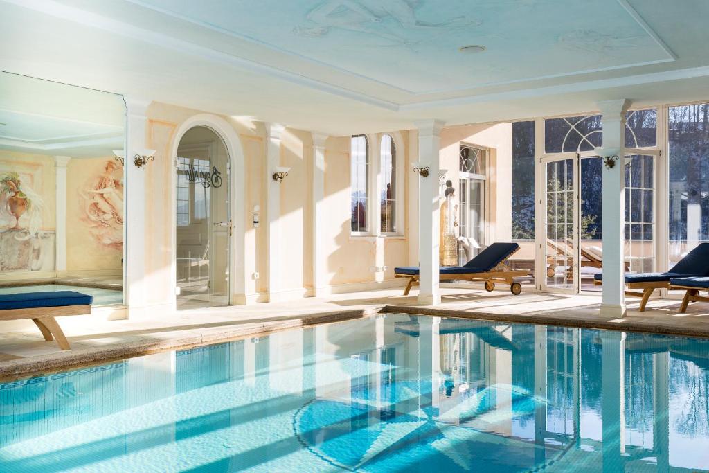 a swimming pool in a room with chairs and a building at Boutiquehotel Bergvilla in Dafins