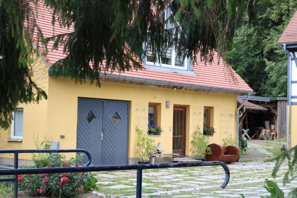 ein kleines gelbes Haus mit blauer Tür in der Unterkunft "Ferienwohnung Am Tharandter Wald" in Grund