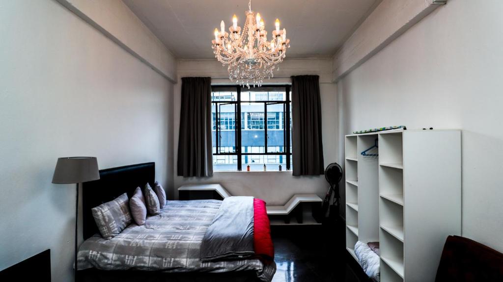 1 dormitorio con cama y lámpara de araña en Maboneng Studio Loft, en Johannesburgo