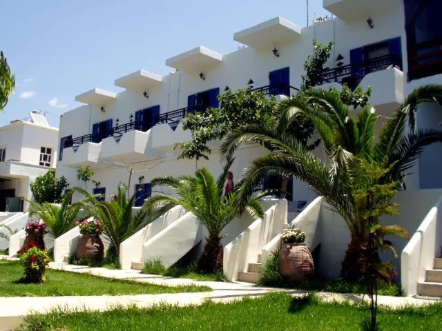 a white building with palm trees in front of it at Oasis Apartments in Frangokastello