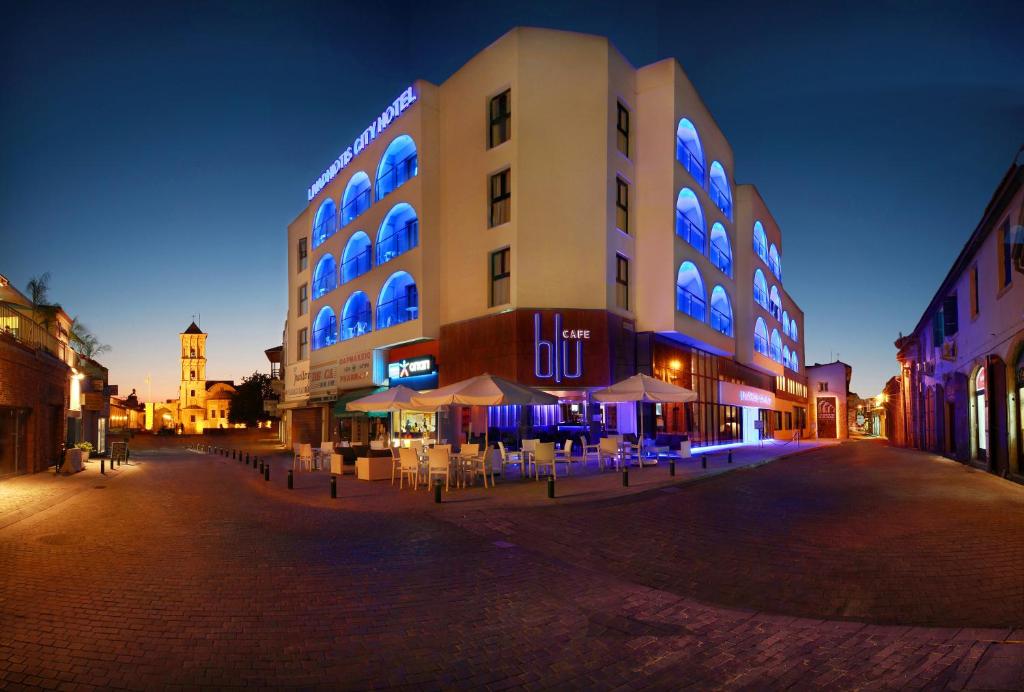 un grand bâtiment avec des lumières bleues allumées la nuit dans l'établissement Livadhiotis City Hotel, à Larnaka