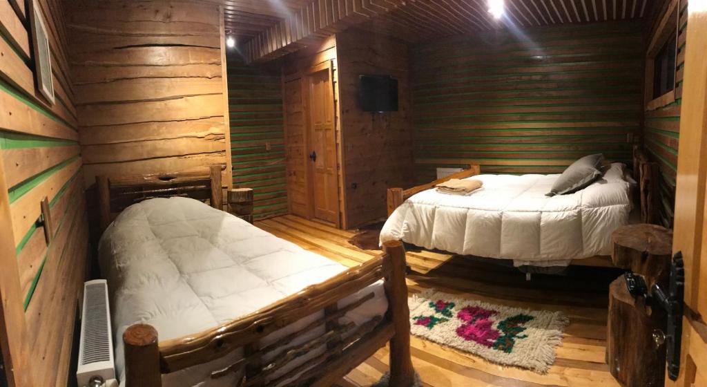 a bedroom with two beds in a log cabin at Hotel Mitos in Quellón