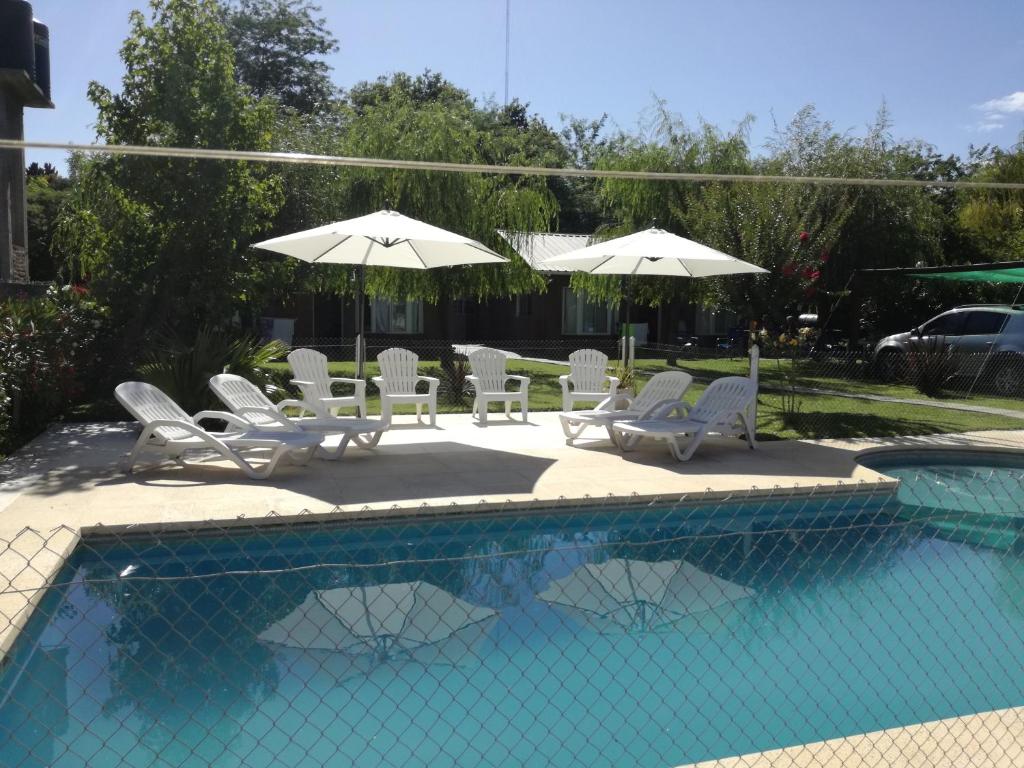 a group of chairs and umbrellas next to a pool at Cabañas Midelem in Chascomús