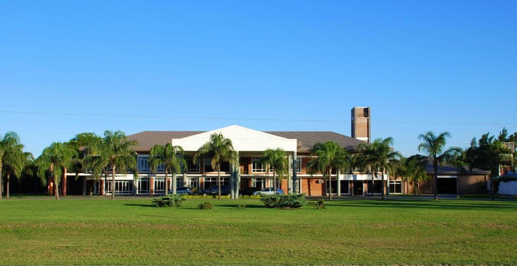 un edificio con palmeras frente a un campo en CATANGE HOTEL en Charata
