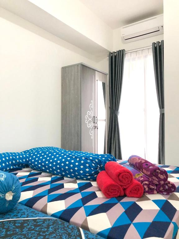 a bedroom with a bed with red and blue at M-Town Residence Gading Serpong by Taslim Property in Tangerang