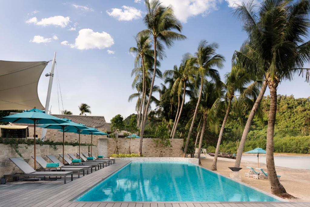 einen Pool mit Stühlen, Sonnenschirmen und Palmen in der Unterkunft Avani Plus Samui Resort in Taling Ngam Beach