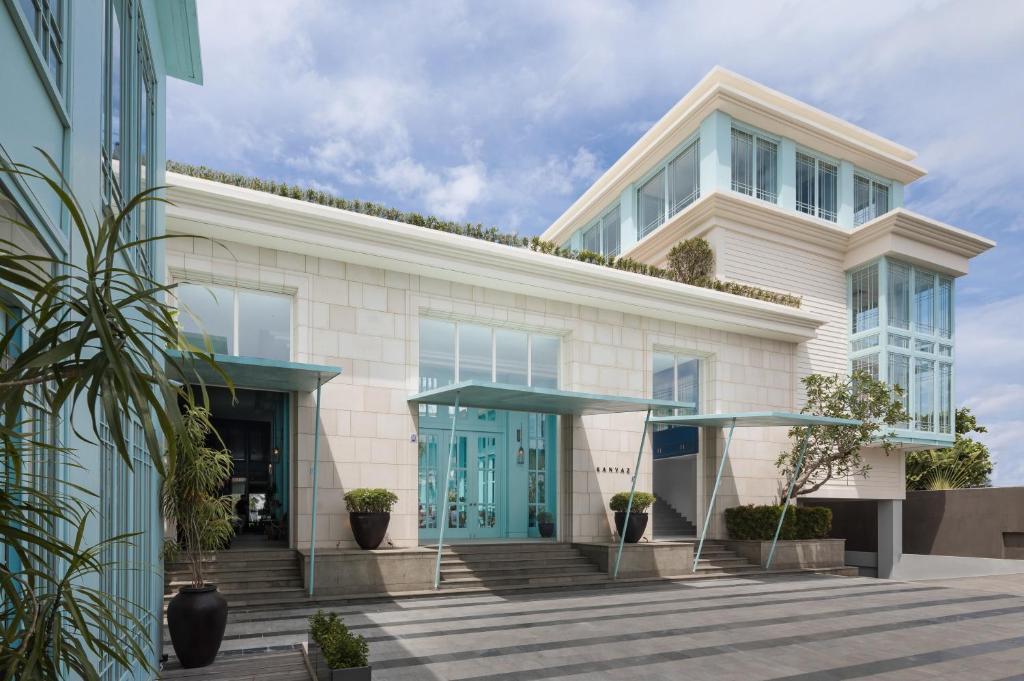 a large white building with blue doors at Kanvaz Village Resort Seminyak in Seminyak