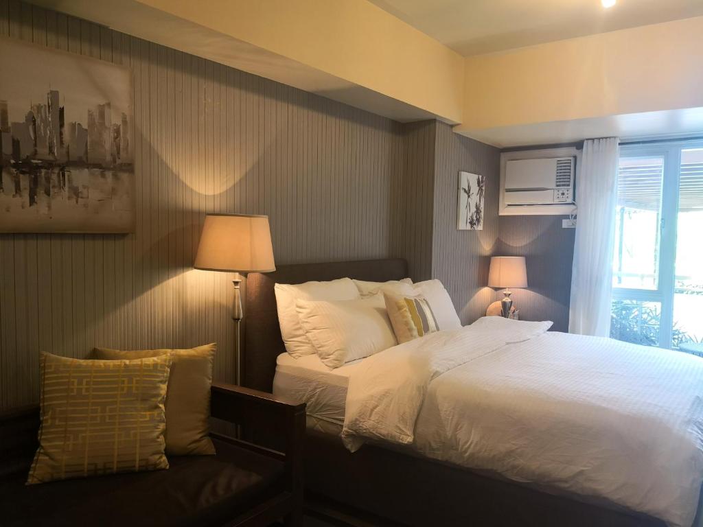 a bedroom with a bed with white sheets and pillows at Centrio Tower Beside Ayala Studio Unit with Balcony 23 in Cagayan de Oro