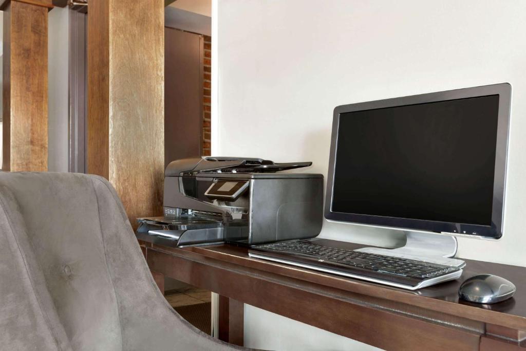 a desk with a computer monitor and a printer at Travelodge Hotel by Wyndham Kingston Lasalle in Kingston
