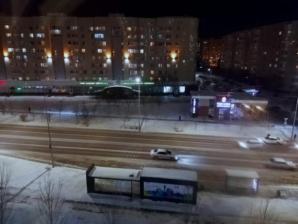a bus driving down a city street at night at Best apartment on Sauran Towers in Astana