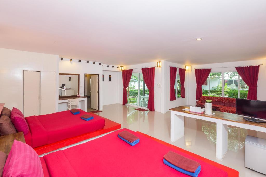 a living room with a red couch and a tv at Da Kanda Villa Beach Resort in Thong Sala