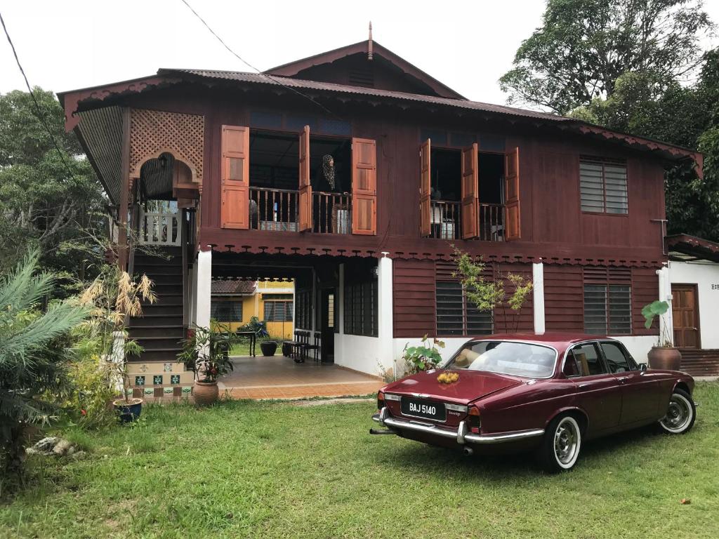 a red car parked in front of a house at Rumah Tiang 16 in Kampong Ulu Jepai
