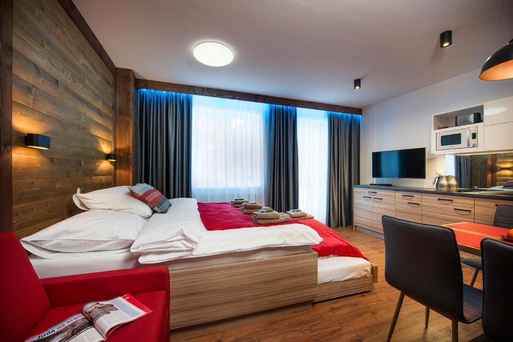 ein Schlafzimmer mit einem großen Bett mit einer roten Decke in der Unterkunft 4Roses Apartments in Starý Smokovec