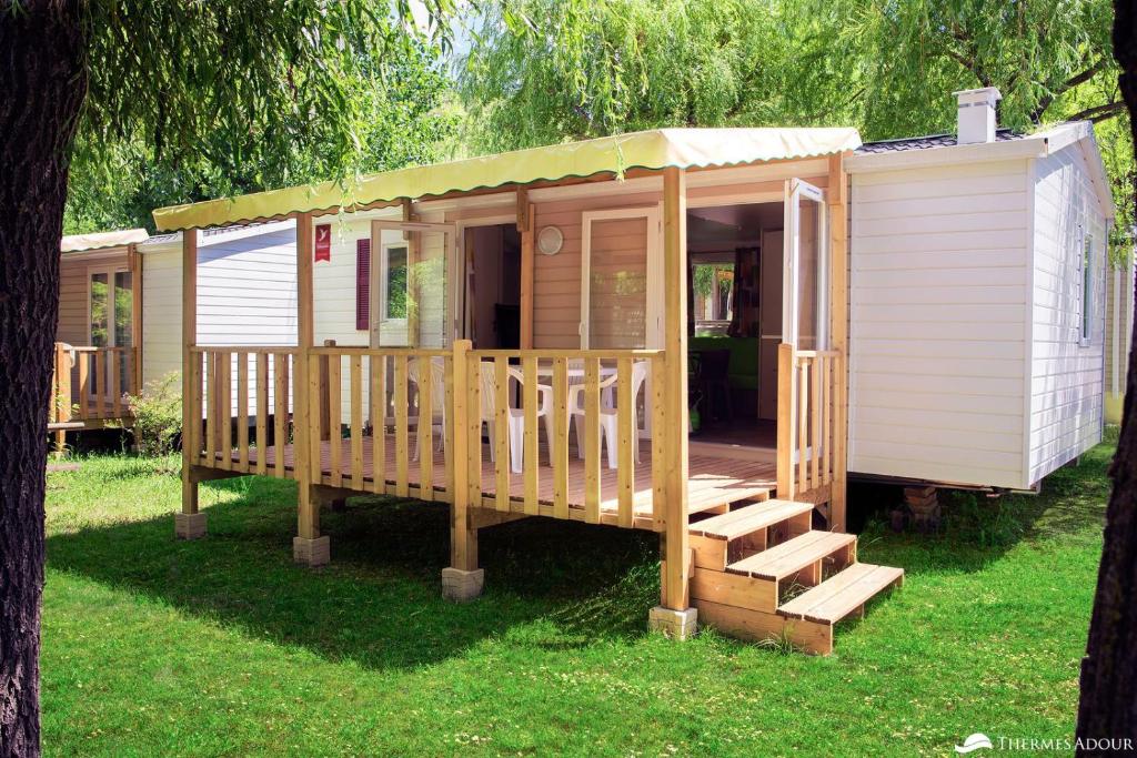 a large wooden cabin with stairs in the grass at Camping des Abesses in Saint-Paul-lès-Dax