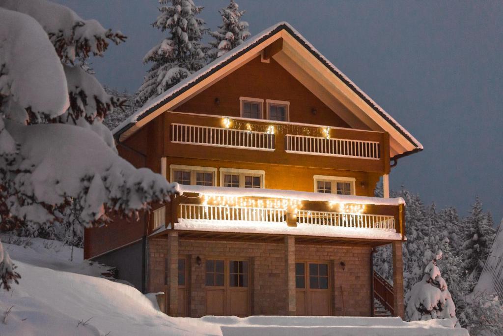 a log home with lights on the balcony in the snow at Holiday Home Kuća za odmor LEA - Ravna Gora in Ravna Gora
