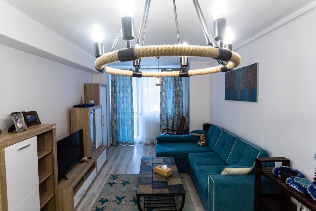 ein Wohnzimmer mit einem blauen Sofa und einem Kronleuchter in der Unterkunft Blue SKY Resort Colina Marei in Sinaia