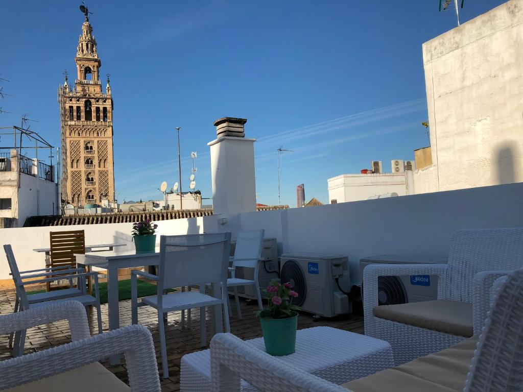una terraza en la azotea con mesas y sillas y una torre del reloj en Abades Giralda View by Valcambre en Sevilla
