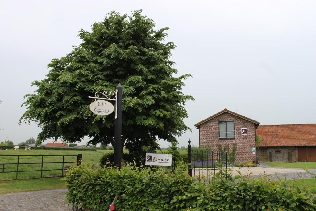 a sign in front of a tree next to a house at B&B Lomolen in Aalter