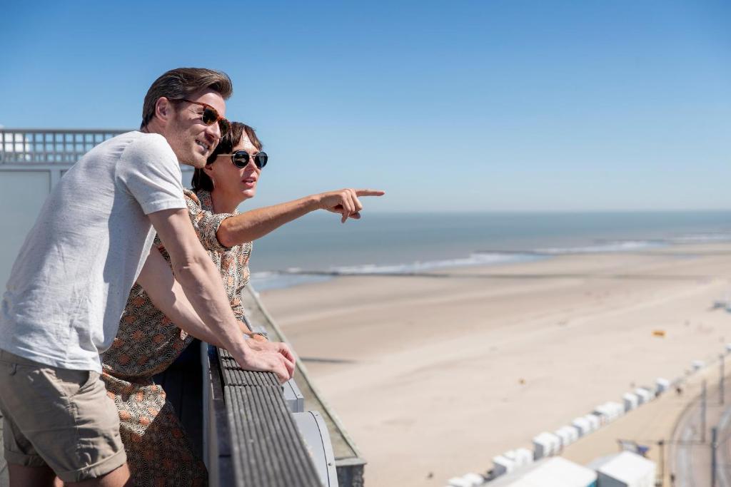 a man and a woman standing next to the beach at C-Hotels Excelsior in Middelkerke