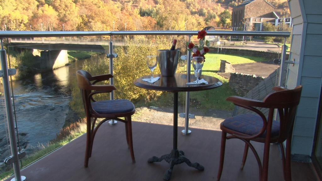 a table and chairs on a balcony with a view of a river at Highland Getaway in Kinlochleven