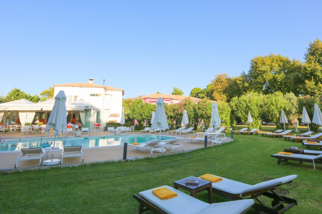 a resort with a pool and lounge chairs and umbrellas at Mandraki Village Boutique Hotel in Koukounaries