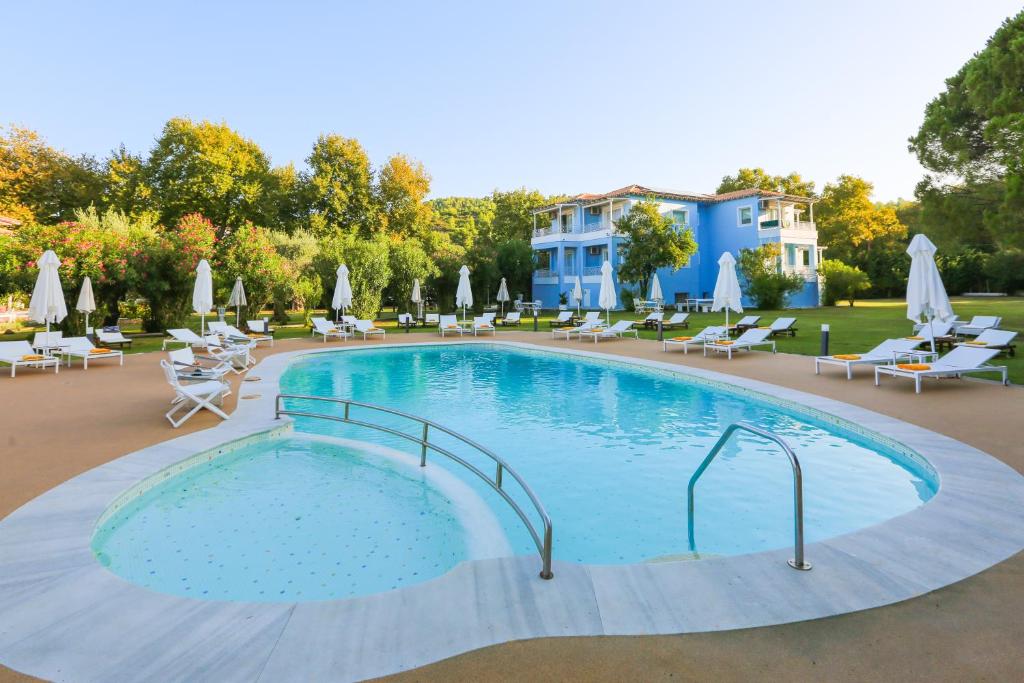 a large swimming pool with chairs and umbrellas at Mandraki Village Boutique Hotel in Koukounaries