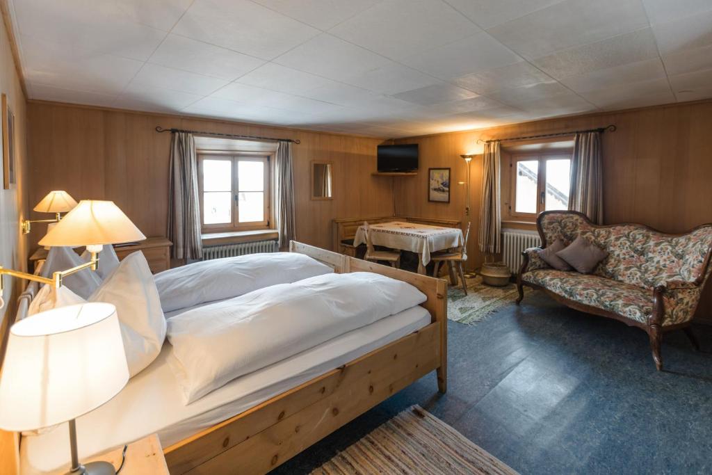 a bedroom with a large bed and a chair at Hotel Klarer in Zuoz
