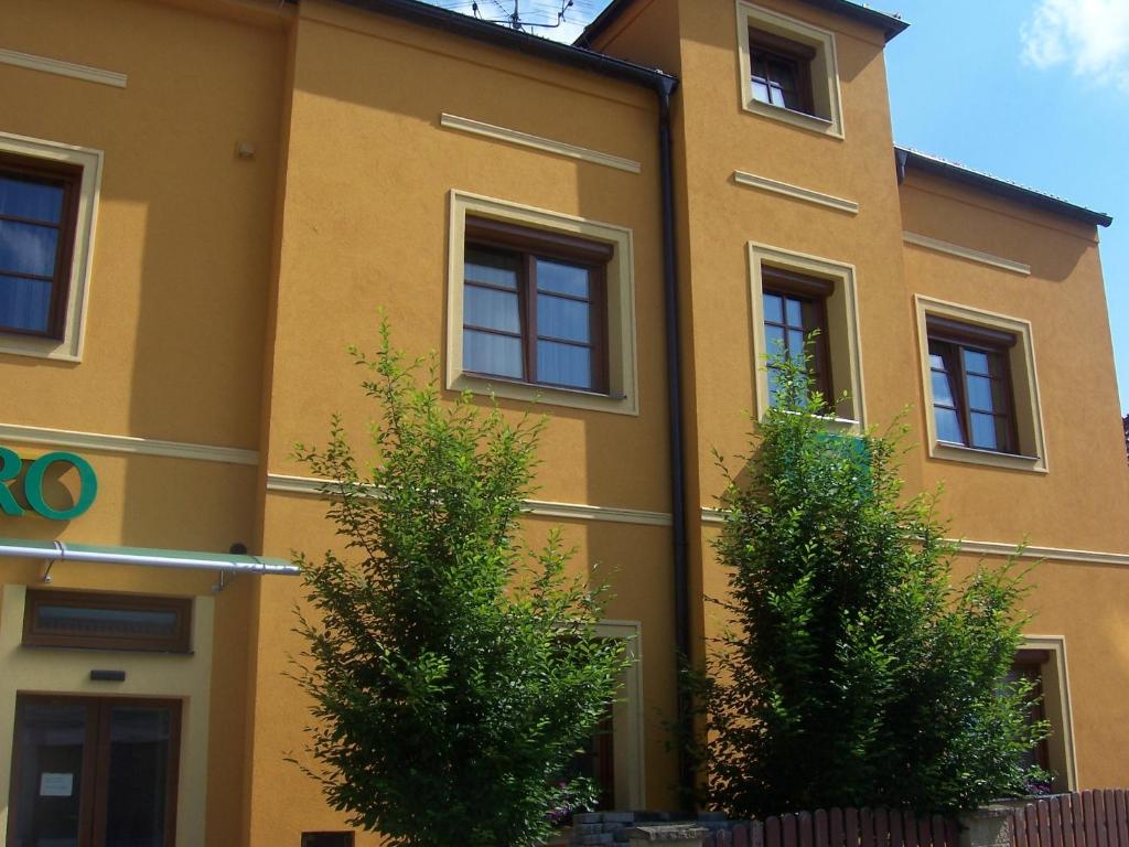 żółty budynek z drzewami przed nim w obiekcie Pension Euro w mieście Mikulov