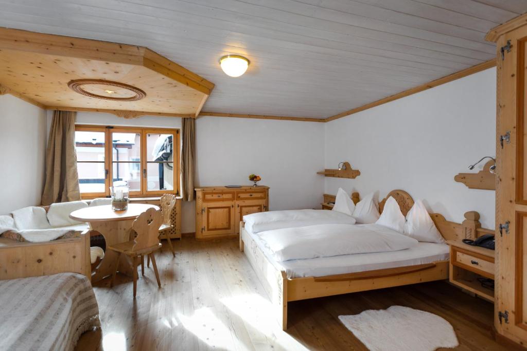 a bedroom with two beds and a desk and a table at Hotel Klarer in Zuoz