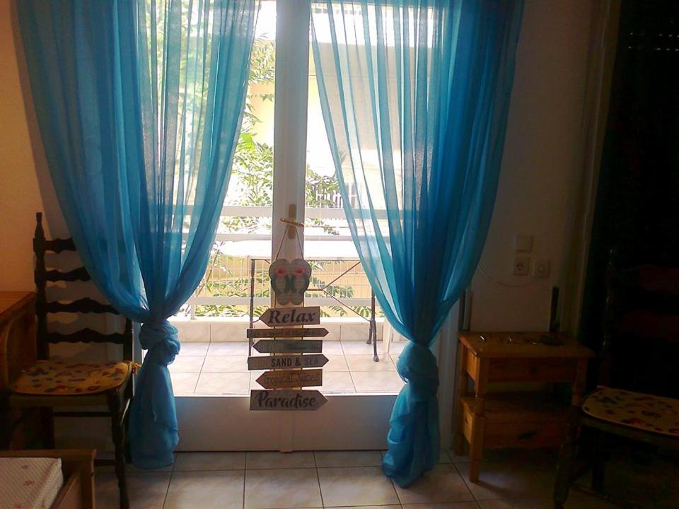 Habitación con cortinas azules y ventana. en Small and cosy appartment- Piccolina, en Loutraki