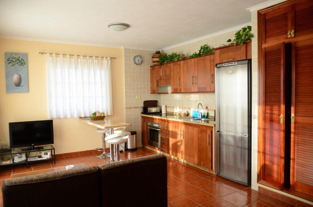 a kitchen with wooden cabinets and a stainless steel refrigerator at Casa Maestro Agustín Nº 1 in Valle Gran Rey