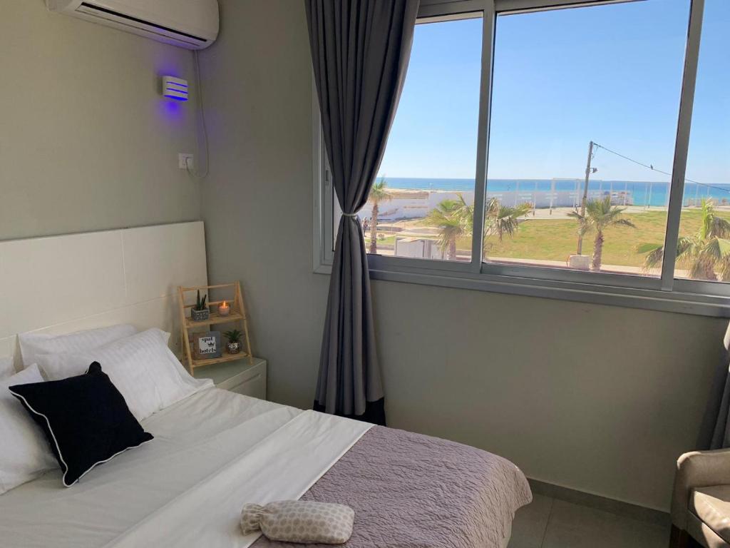 a bedroom with a bed and a large window at Motel Hofim in Bat Yam