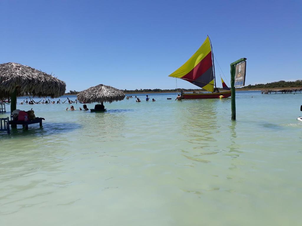 a beach with people in the water and a sail boat at Suíte central Pousada in Jijoca de Jericoacoara